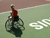 A woman in a wheelchair waits on a tennis court